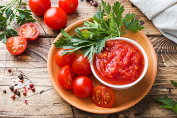 Tomato sauce pasta in a bowl and fresh tomatoes with parsley on a wooden table