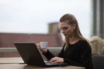Young beautiful woman using laptop and drinking coffee
