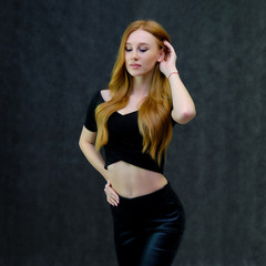 Concept portrait of a cute beautiful red-haired girl talking on a gray background in the studio