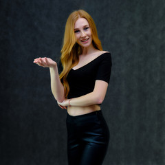 Concept portrait of a cute beautiful red-haired girl talking on a gray background in the studio