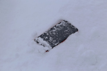 雪の上に落ちたスマートフォン
