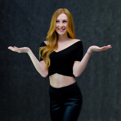 Concept portrait of a cute beautiful red-haired girl talking on a gray background in the studio