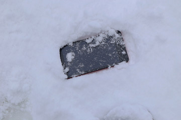 雪の上に落ちたスマートフォン