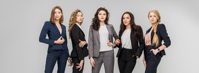 beautiful successful women standing with hands in pockets isolated on grey