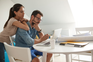 Husband and wife sitting at home and  buying online stocks actions.