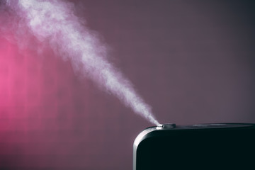 black humidifier on pink background with white steam