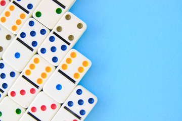 White dominoes with brightly colored dots on blue background shot overhead with copy space