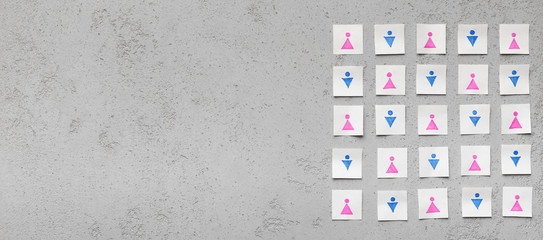 Paper cards with men and women icons on gray concrete table