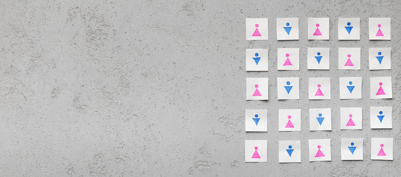 Paper cards with men and women icons on gray concrete table