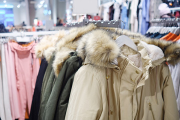 Rack with trendy warm jackets of different colors in clothes shop