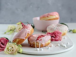 A stack of pink donuts with flowers on a dark background