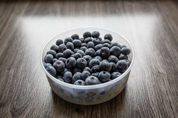 Ripe tasty blueberries and berries on a wooden table in a bowl