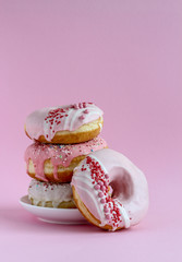 A stack of pink donuts on a pink background