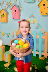 Fototapeta na wymiar Cute smiling little girl with basket full of colorful easter eggs