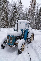 old blue tractor standing covered in snow