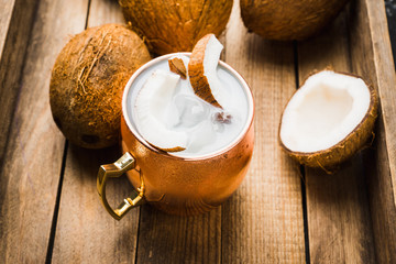 Sweet coconut cocktail in copper mug (variation of Moscow mule) on the wooden background. Selective...