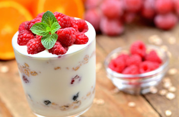 Homemade bio yogurt, raspberries and mint leaves, oranges, grapes and glass of oatmeals in...