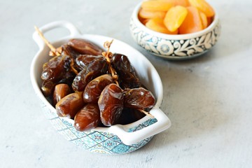 Bowls with juicy dates on a branch and dried apricots on a gray-blue background. Healthy tasty food, snack