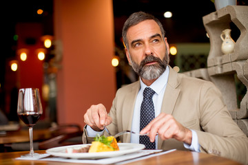 Handsome senior man eating lunch in restaurant