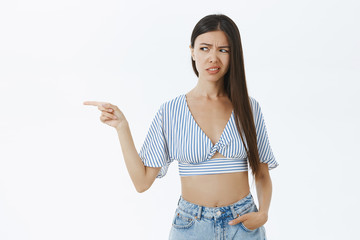 Waist-up shot of displeased and unimpressed snobbish asian girl with dark hair frowning from...