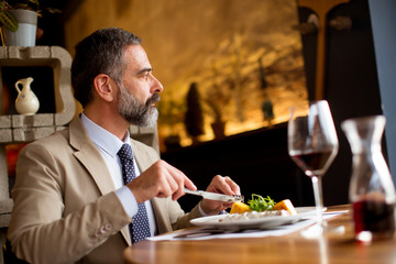 Handsome senior man eating lunch in restaurant