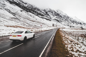 Car driving on open road winter snow mountain landscape in Glencoe Scotland