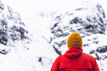Fototapeta na wymiar Man standing by mountain landscape in winter snow Glencoe Scotland