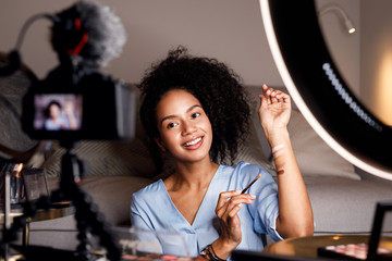 Young woman recording video for her online course. Makeup artist with palette of tonal creams on...