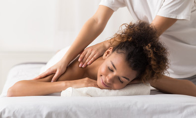 Masseur doing shoulder massage on woman body