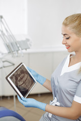 Dentist doctor using digital tablet against dental equipment.