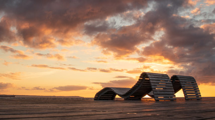 Sun beds during a colorful sunset overlooking the ocean in Helsingborg, Sweden at the popular...