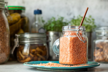 Dry red lentils in a jar on the kitchen table.
