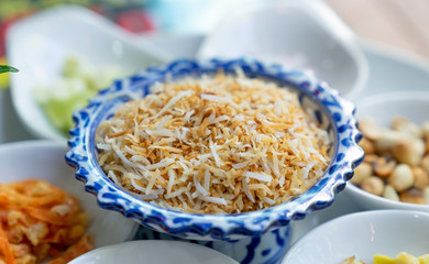 close up crispy sliced coconut on white spoon for miang kum ingredient
