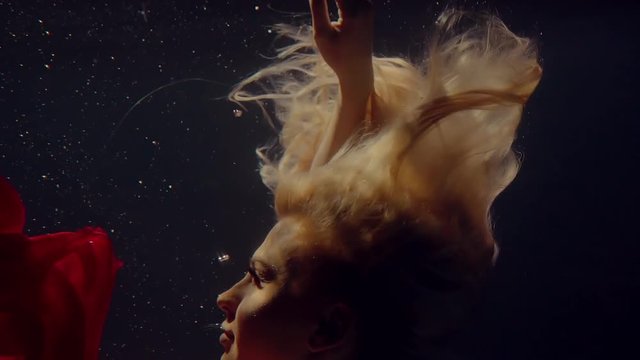 Beautiful blonde girl floats underwater.