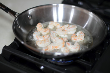 Shrimp cooking in a stainless steel pan on the stove.