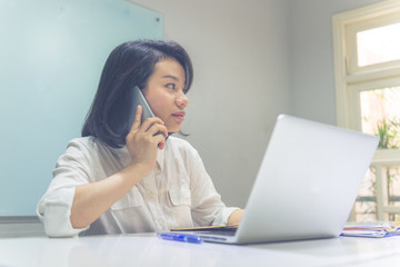 Asian businesswoman talking on cellphone at office