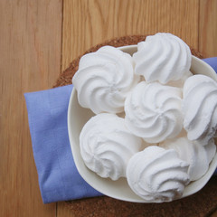 Small white meringues in a bowl on wooden table