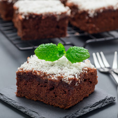 Homemade brownie with coconut flakes, swedish dessert Karleksmums, cut in square servings, on stone...