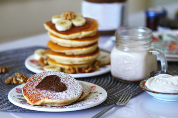 Breakfast pancakes served with honey and fruits and milk
