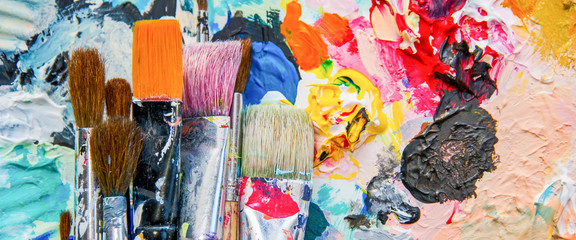 Fototapeta Used paint brushes on a colorful painter palette obraz