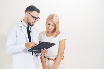 Male doctor and female patient with documents of patients health record are having conversation in...