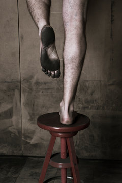 Des pieds sur un tabouret montrant la plante des pieds sale