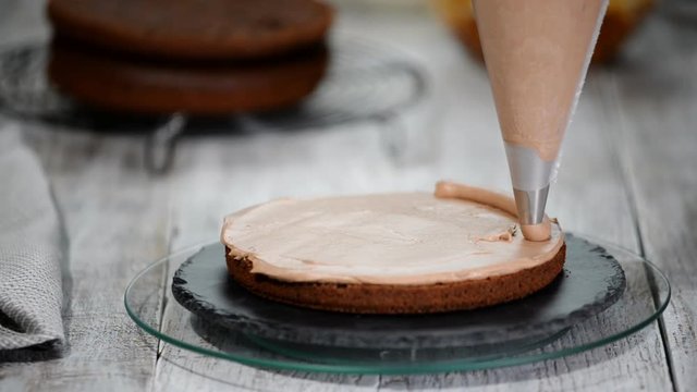 The confectioner making chocolate cake with caramel peanuts. Step by step assembly chocolate ceke