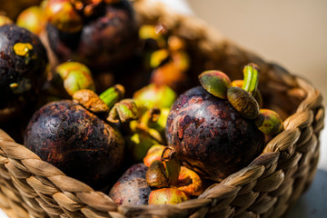 Fresh ripe mangosteens in basket. Asian fruit - purple mangosteen or garcinia mangostana. Closeup. Thai exotic fruits.