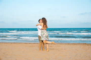 Fototapeta na wymiar Euphoric young couple meeting and hugging on the sea beach. Horizontal shape, side view, copy space..Happy lovers.