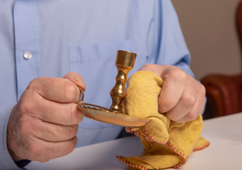 Unrecognisable man polishing brass candle sticks at home