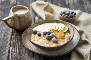 Oatmeal, healthy porridge in large bowl with fruits and berry for breakfast, cup of cocoa. Side...