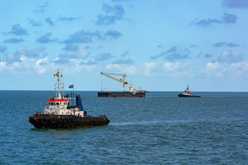 Tugboats assists Floating Crane Transhipper in Bauxite transshipment operations at anchorage off Port Kamsar, Republic of Guinea.