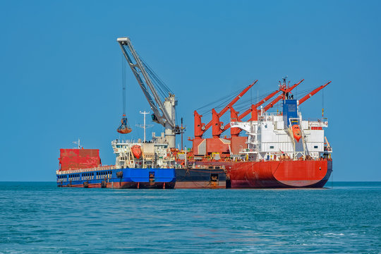 Loading Ocean-going Bulk Carrier Ship With Bauxite Aluminum Ore From The Mini Bulk Carrier (feeder) Vessel At Offshore Kamsar Port, Guinea, West Africa.