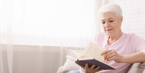 Old lady reading book on sofa at home